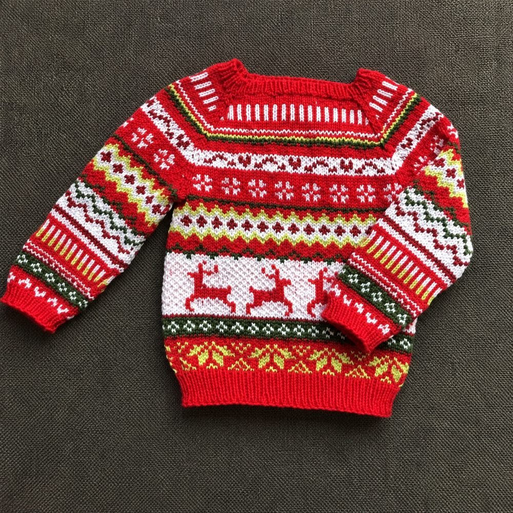 Red Fair Isle knitted baby Christmas jumper with reindeer and snowflake colorwork bands, from the Sweet Christmas pattern by Erna de Groot