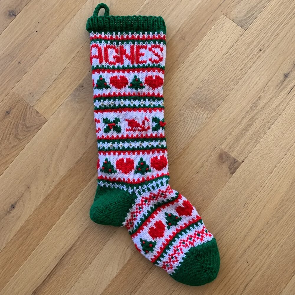 Fair Isle knitted Christmas stocking with rows of hearts and trees in red, green, pink and white, from Freese-Works