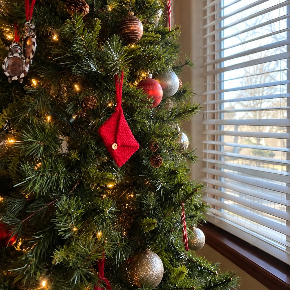 Small red garter stitch knitted envelope ornament hanging on a Christmas tree, from Heart Hook Home