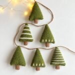 Little green knitted Christmas tree ornaments, some with white stripes, strung on a garland, DROPS Christmas Woods