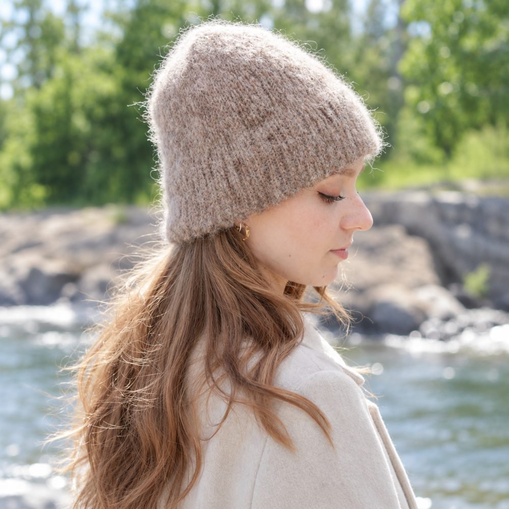 Fluffy beige knitted hat with a double fold worn outdoors, DROPS Fawn Frill Hat