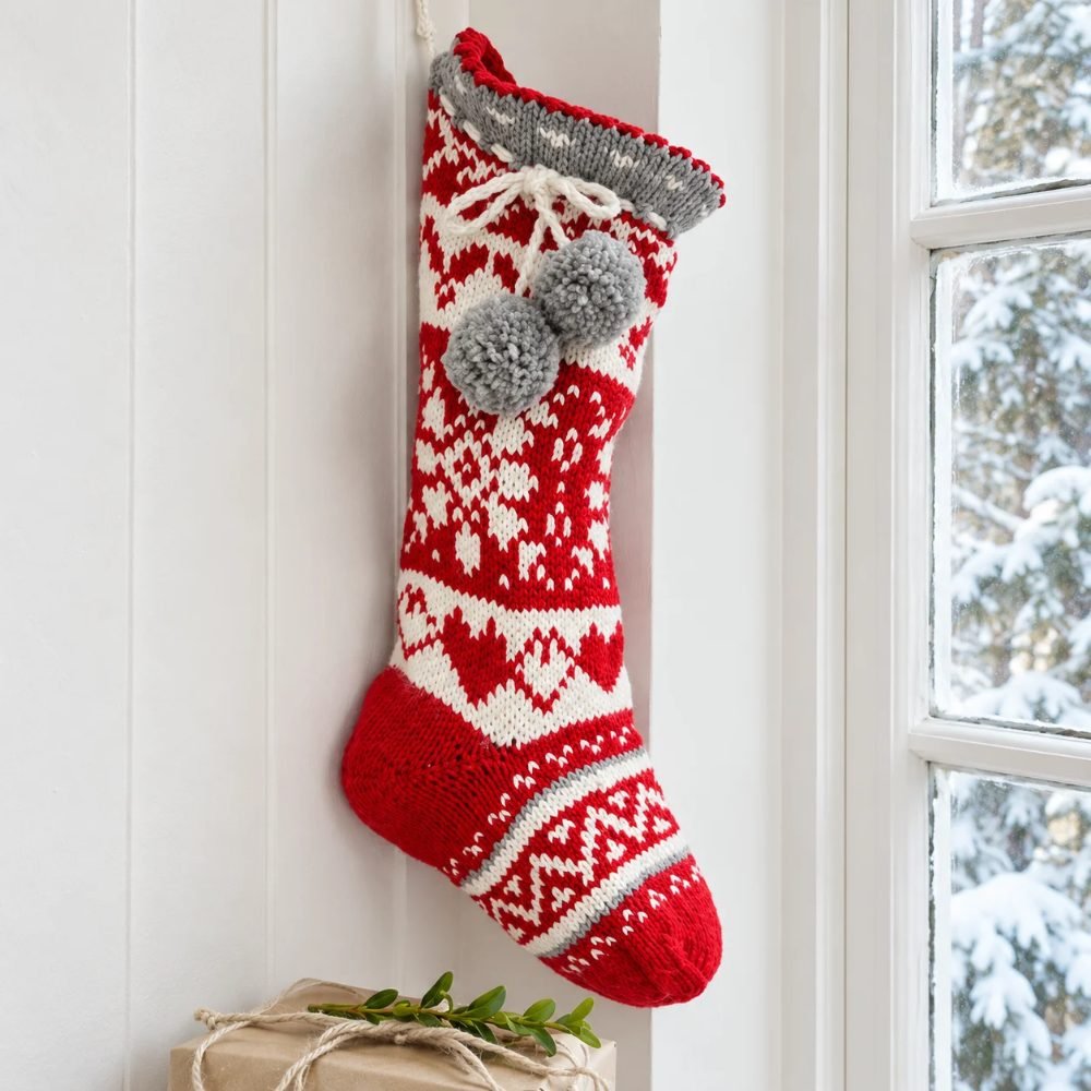 Red Nordic-patterned knitted Christmas stocking with white motifs, a grey cuff and pompoms, DROPS Sweet Treasures