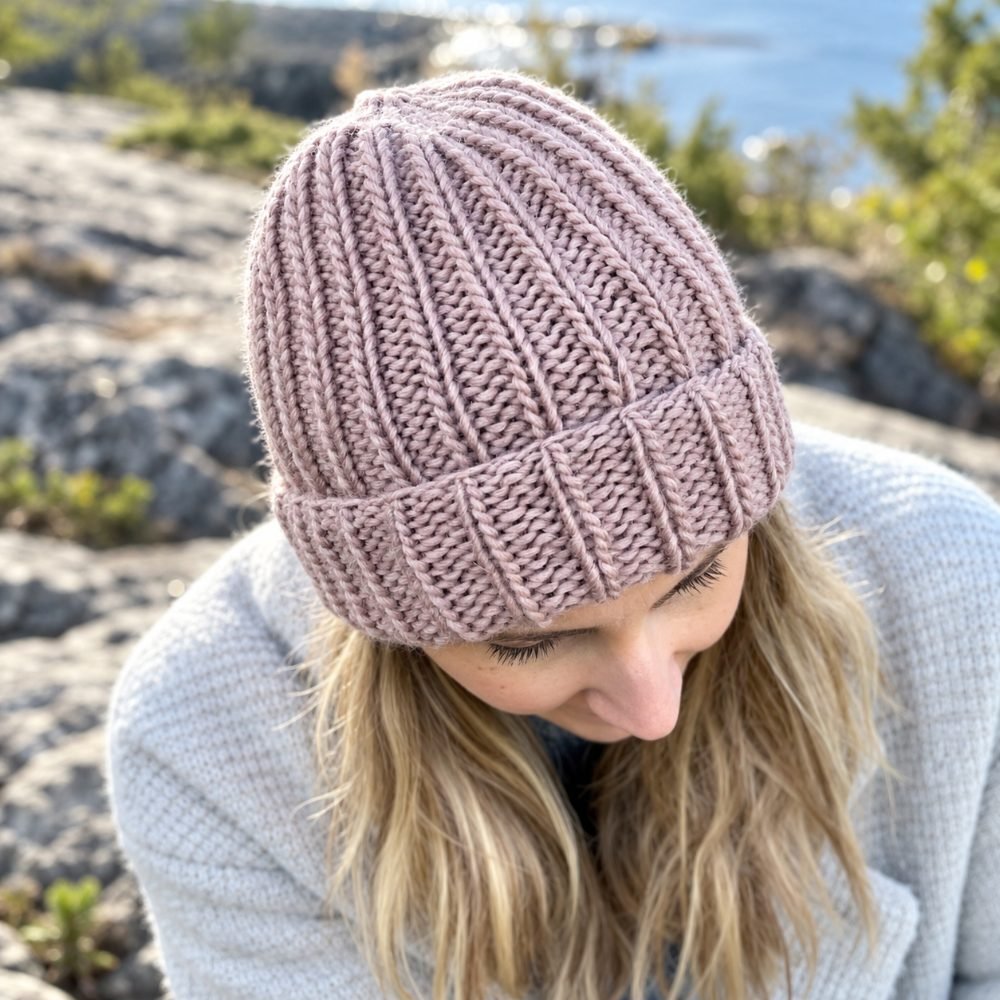 Mauve ribbed knitted beanie with a folded brim worn outdoors by the sea, from the How to Knit a Hat with Straight Needles pattern by Handy Little Me