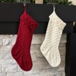 Red and cream cable knitted Christmas stockings hanging from a mantel, from Leelee Knits